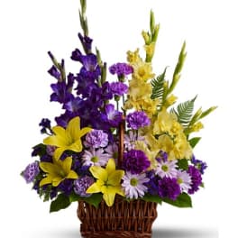 Purple and yellow mixed flower arrangement in a wicker basket