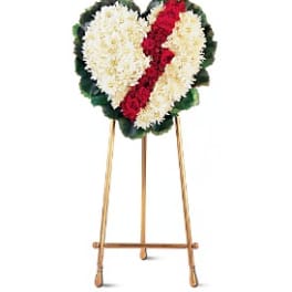 Heart-shaped funeral wreath of white and red flowers on a stand