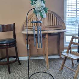 Wind chime with a white bow and green topper on a black stand