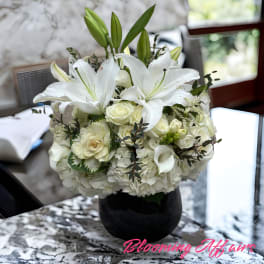 White lilies and roses arranged in a black vase