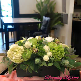 Green and white floral arrangement in a black rectangular box
