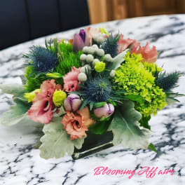 Compact mixed bouquet with pink, purple, and green blooms in a low glass vase
