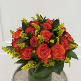 Bouquet of red-orange roses in a glass vase with yellow filler flowers