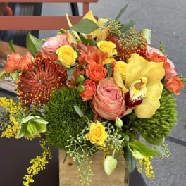 Colorful floral arrangement in a wooden box with roses and orchids
