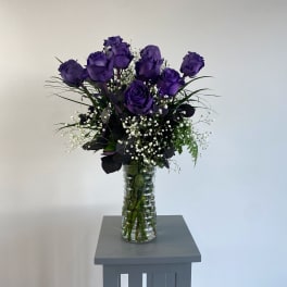 Purple roses in a clear glass vase with white baby's breath