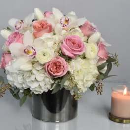 Pink and white bouquet in a silver vase beside a lit candle
