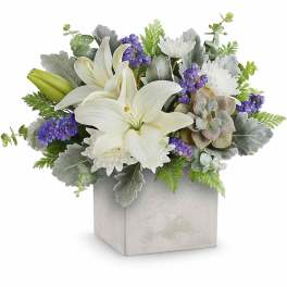 White lilies and purple flowers in a square gray vase