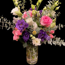 Pink and purple bouquet in a glass vase with eucalyptus