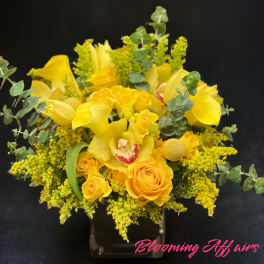 Yellow roses and calla lilies in a clear vase with eucalyptus