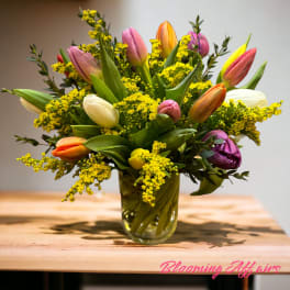 Mixed tulip bouquet in a glass vase with yellow filler flowers