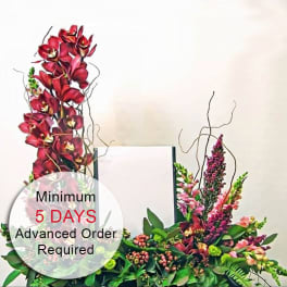 Tall red and pink floral arrangement framing a central white panel with curving branches.
