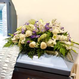 White and purple floral spray on a casket