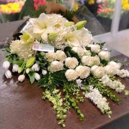 White floral bouquet with roses, lilies, and tulips wrapped in clear plastic