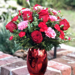 Red roses and pink carnations in a red glass vase