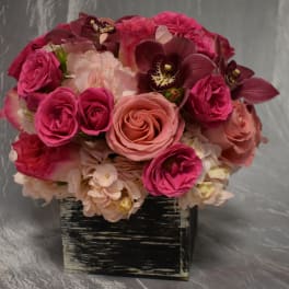 Pink and peach roses with orchids in a black square container