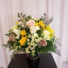 Mixed bouquet of roses and small white daisies in a black vase