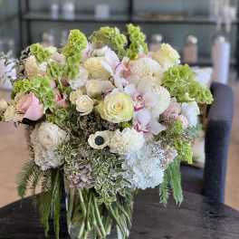 Mixed bouquet in a clear glass vase with white, pink, and green blooms