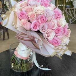 Bouquet of pink and white roses wrapped in pastel paper with ribbon
