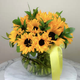Bouquet of yellow sunflowers in a glass vase with a yellow ribbon