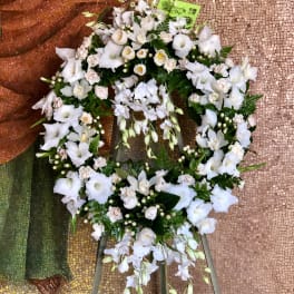 White floral wreath on a stand with trailing blooms