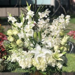 White lilies and orchids arranged in a wicker basket
