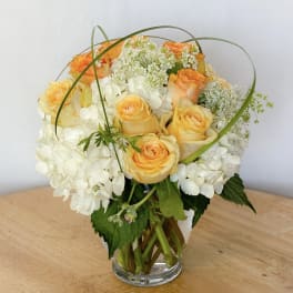 Bouquet of peach roses and white hydrangeas in a clear glass vase
