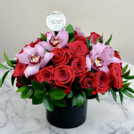 Red roses and pink orchids arranged in a black box