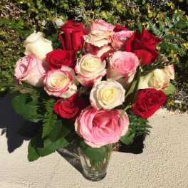 Bouquet of red, pink, and white roses in a clear glass vase