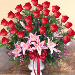 Red roses and pink lilies in a white vase with a red ribbon