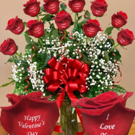 Red roses with baby’s breath in a glass vase and a large red bow
