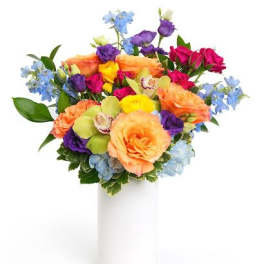 Colorful bouquet of peach roses and mixed bright blooms in a white cylinder vase