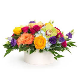 Low arrangement of bright mixed flowers in a white round vase