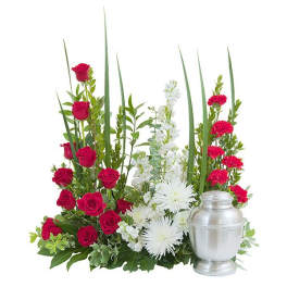 Red and white sympathy arrangement with roses, carnations, and a silver urn
