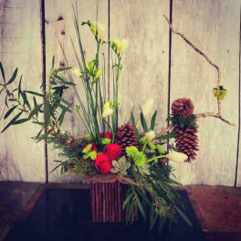 Mixed floral arrangement with red roses, white blooms, and pinecones in a rustic container