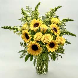 Yellow sunflowers and roses in a clear glass vase
