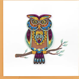 Colorful quilled owl perched on a branch against a white background