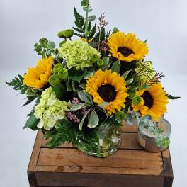 Bouquet of sunflowers and pale green hydrangeas in a glass vase