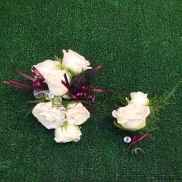 White rose boutonnieres with burgundy ribbon on green turf