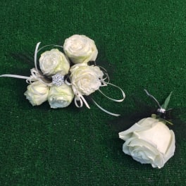 White rose corsage and matching boutonniere on green grass