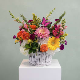 Colorful mixed flower arrangement in a white wicker basket