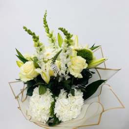 Bouquet of white and pale yellow flowers wrapped in clear paper with gold trim