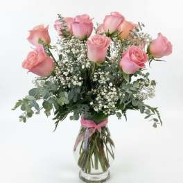 Pink roses arranged in a clear glass vase with baby's breath