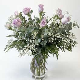 Lavender roses in a clear glass vase with baby's breath