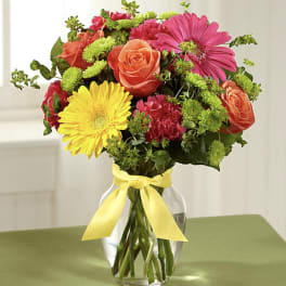 Mixed bouquet of roses, gerbera daisies, and carnations in a glass vase