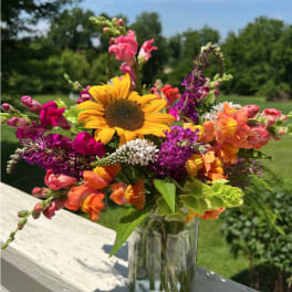 Colorful bouquet with a sunflower and snapdragons in a glass vase
