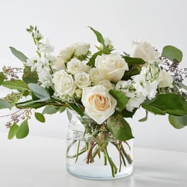 White roses and stock in a clear glass vase