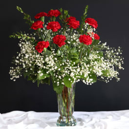 Red carnations and white baby's breath in a clear glass vase