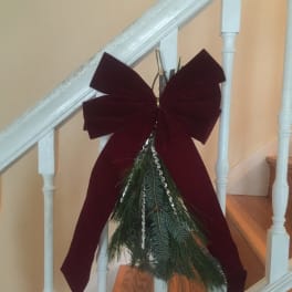 Holiday bow with evergreen sprigs hanging on a staircase railing