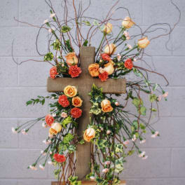 Floral cross arrangement with peach roses and orange carnations