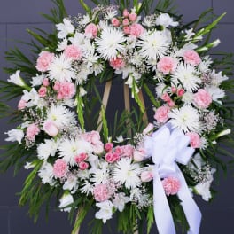 Pink and white floral wreath on a standing easel with a white ribbon